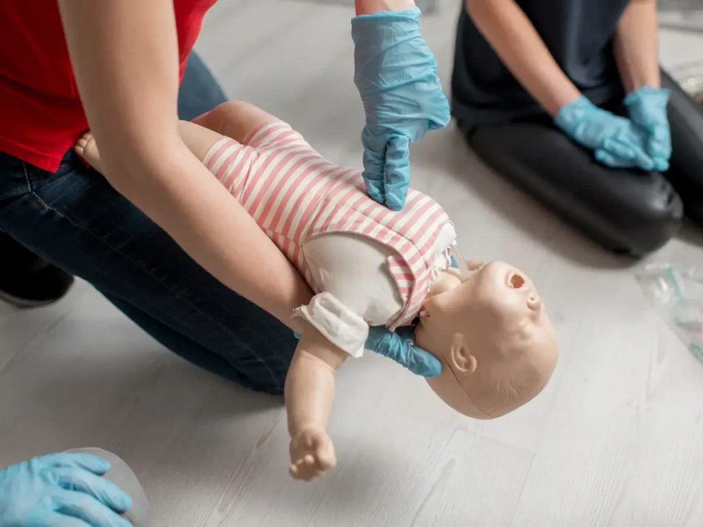 Ragazza che mostra le manovre di disostruzione pediatrica utilizzando un bambolotto.